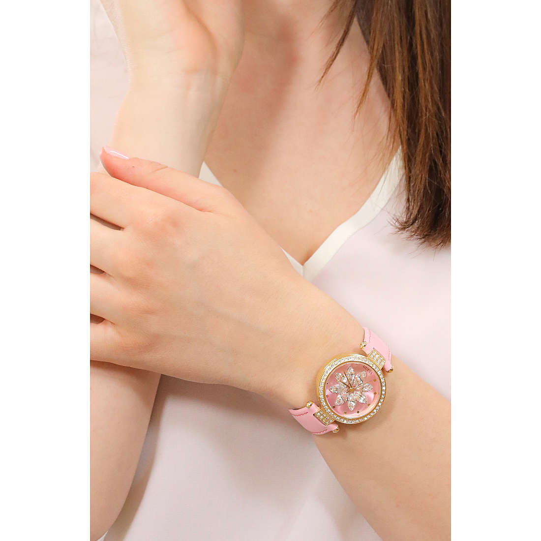 Pink analog watch on woman's wrist showcasing floral design and gold accents