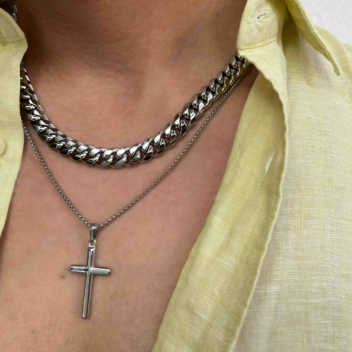 RADIANT JEWELS JEWELRY Mod. RH000108 silver chain and cross necklace worn with a yellow shirt.