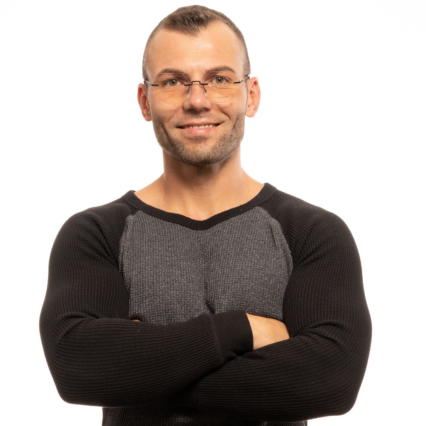 Man wearing Yohji Yamamoto Black Metal Glasses (Frames) with rimless style and black frame, arms crossed, against white background.