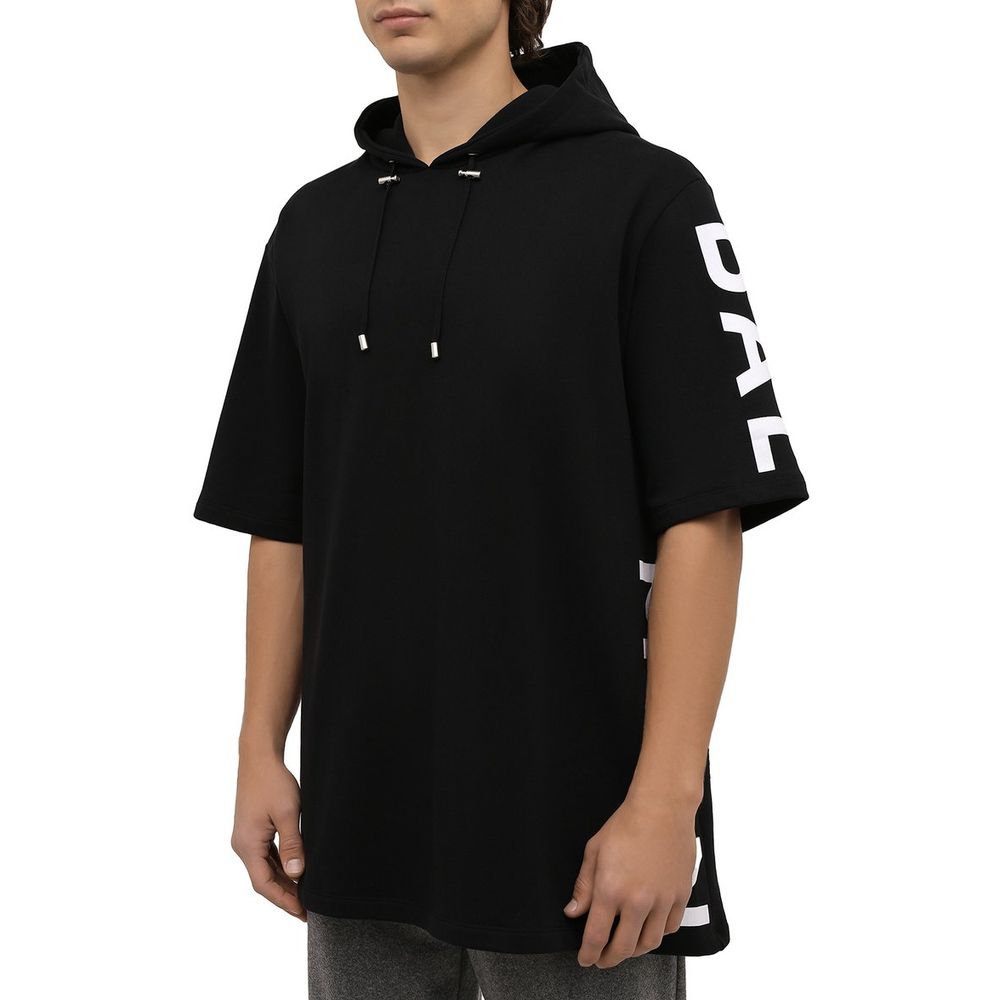 Male model wearing Balmain Black Cotton Sweater with hood and logo print on side, showcasing half-sleeve design.