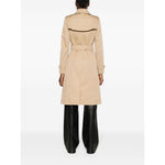 Back view of model wearing Burberry Double-breasted cotton trench coat in beige with belt, knee-length, and classic features.