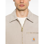 Man wearing CARHARTT WIP MAIN Jackets Beige with zip fastening and chest pocket, showing front design.