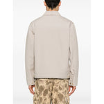 Back view of CARHARTT WIP MAIN Jackets Beige, canvas jacket with press-stud cuffs, worn with camo pants.