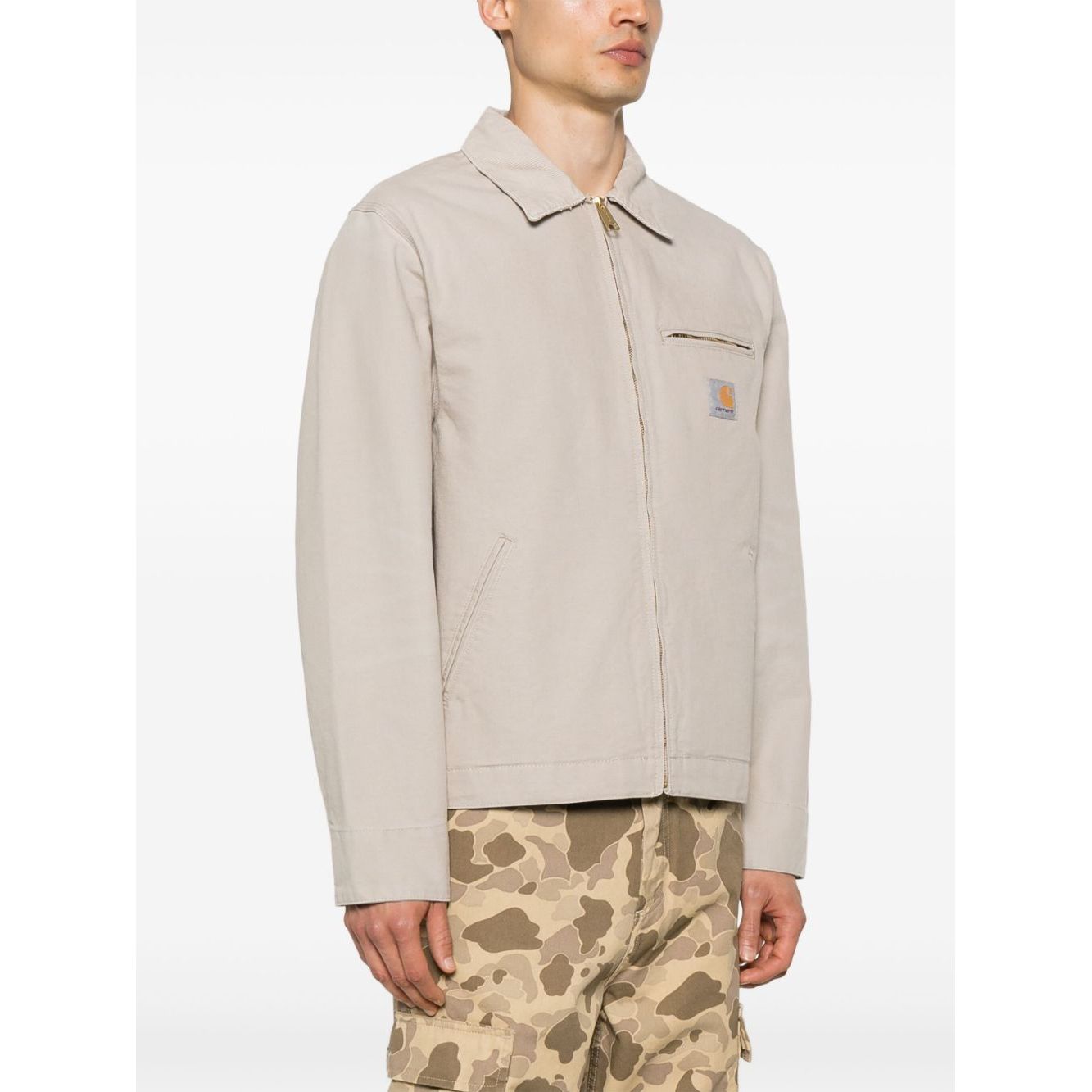 Alt Tag: Model wearing CARHARTT WIP MAIN Jackets Beige with zip fastening and front pockets, ideal for casual style.