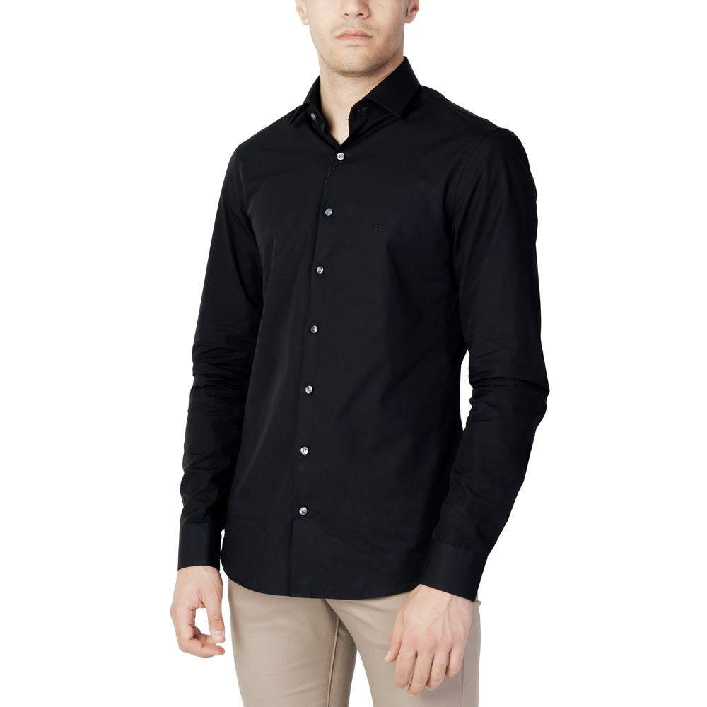 Man wearing a Calvin Klein Black Cotton Dress Shirt, featuring a slim fit and minimalist design in 100% poplin cotton.