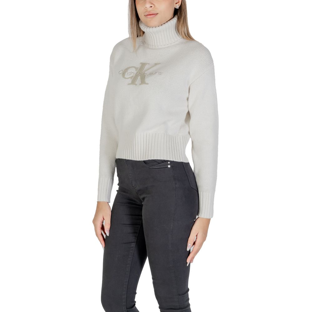 Woman wearing Calvin Klein Jeans Cream Cotton Sweater with CK logo, ribbed turtleneck, crafted from cotton-acrylic blend.