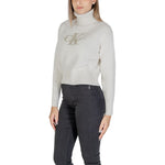 Woman wearing Calvin Klein Jeans Cream Cotton Sweater with CK logo, ribbed turtleneck, crafted from cotton-acrylic blend.