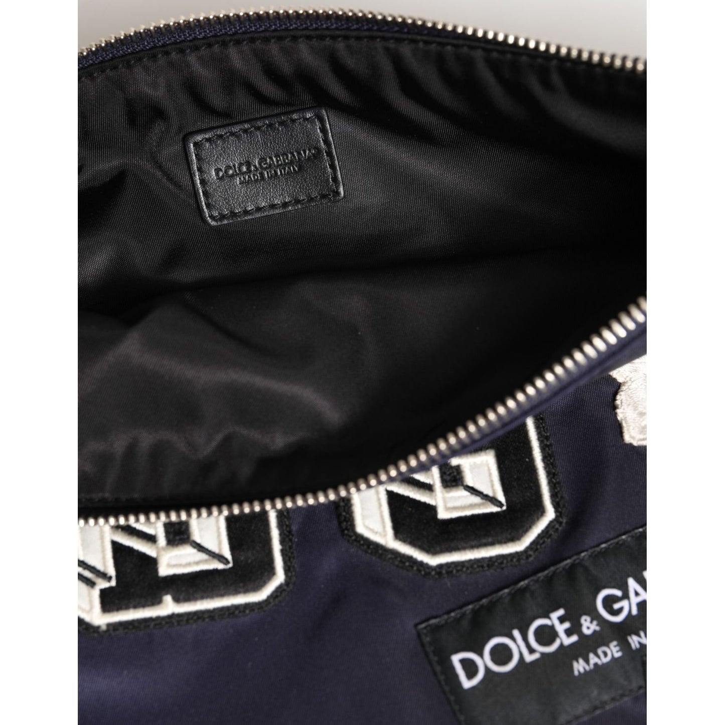 Close-up of Dolce & Gabbana Blue DG Logo Patch Embellished Pouch Clutch Men Borse Bag showing interior with zip and logo details.
