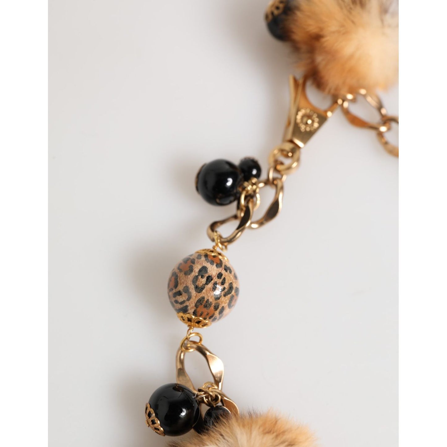 Close-up of Dolce & Gabbana Gold Black Crystals Lapin Fur Filigree Choker Necklace with leopard-print beads and pom-poms.