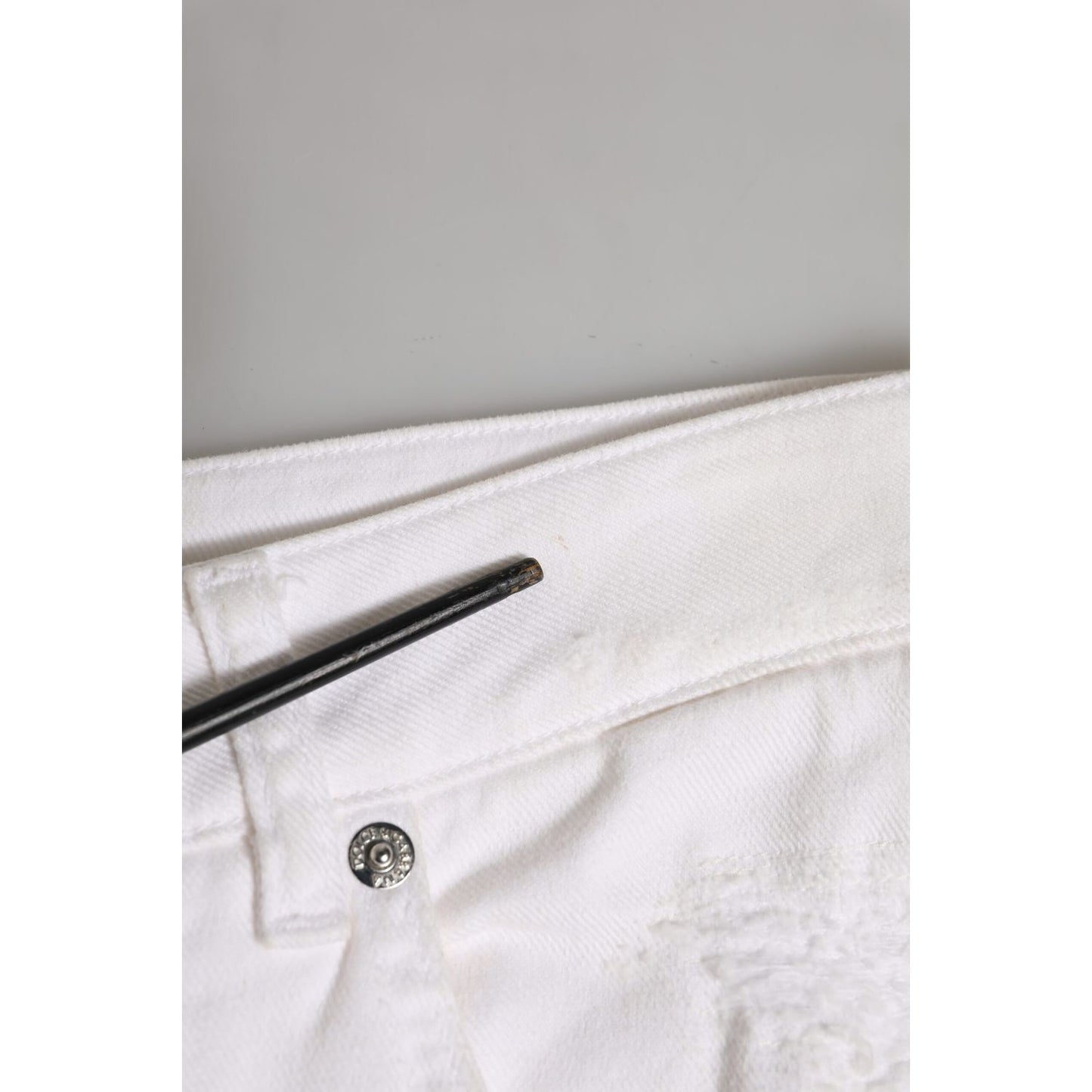 Close-up of Dolce & Gabbana White Cotton Tattered BOYFRIEND Denim Jeans showcasing button and fabric details.