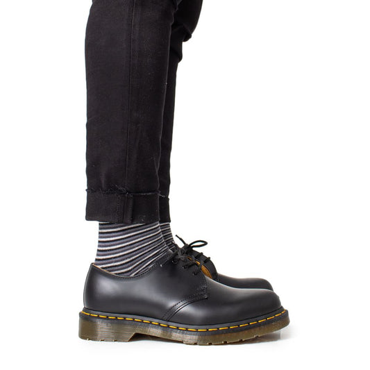 Person wearing Dr. Martens Black Leather Oxfords And Derby with striped socks and black pants