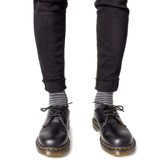 Man wearing Dr. Martens Black Leather Oxfords And Derby with striped socks and black pants
