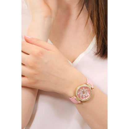 Pink analog watch on woman's wrist showcasing floral design and gold accents