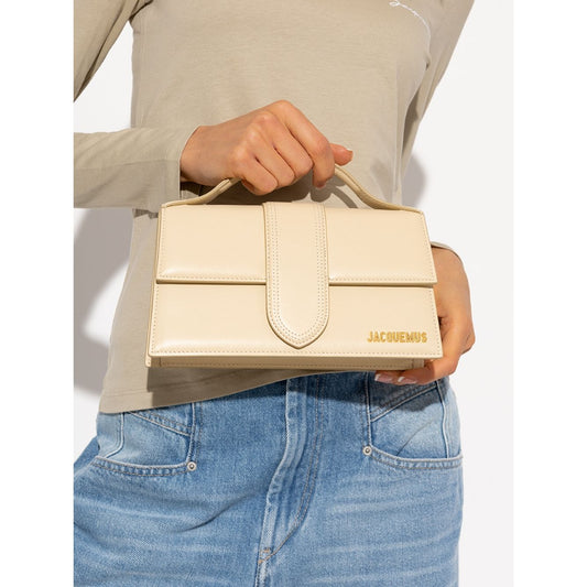 Woman holding Jacquemus Le Grand Bambino Beige Bag with gold hardware and adjustable strap.