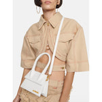 Jacquemus White Le Chiquito Moyen Bag with Gold Hardware, worn crossbody by model in beige outfit.