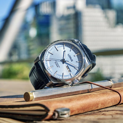 LORUS WATCHES Mod. RL417CX9 sleek silver timepiece with black leather strap displayed on a notebook outdoors