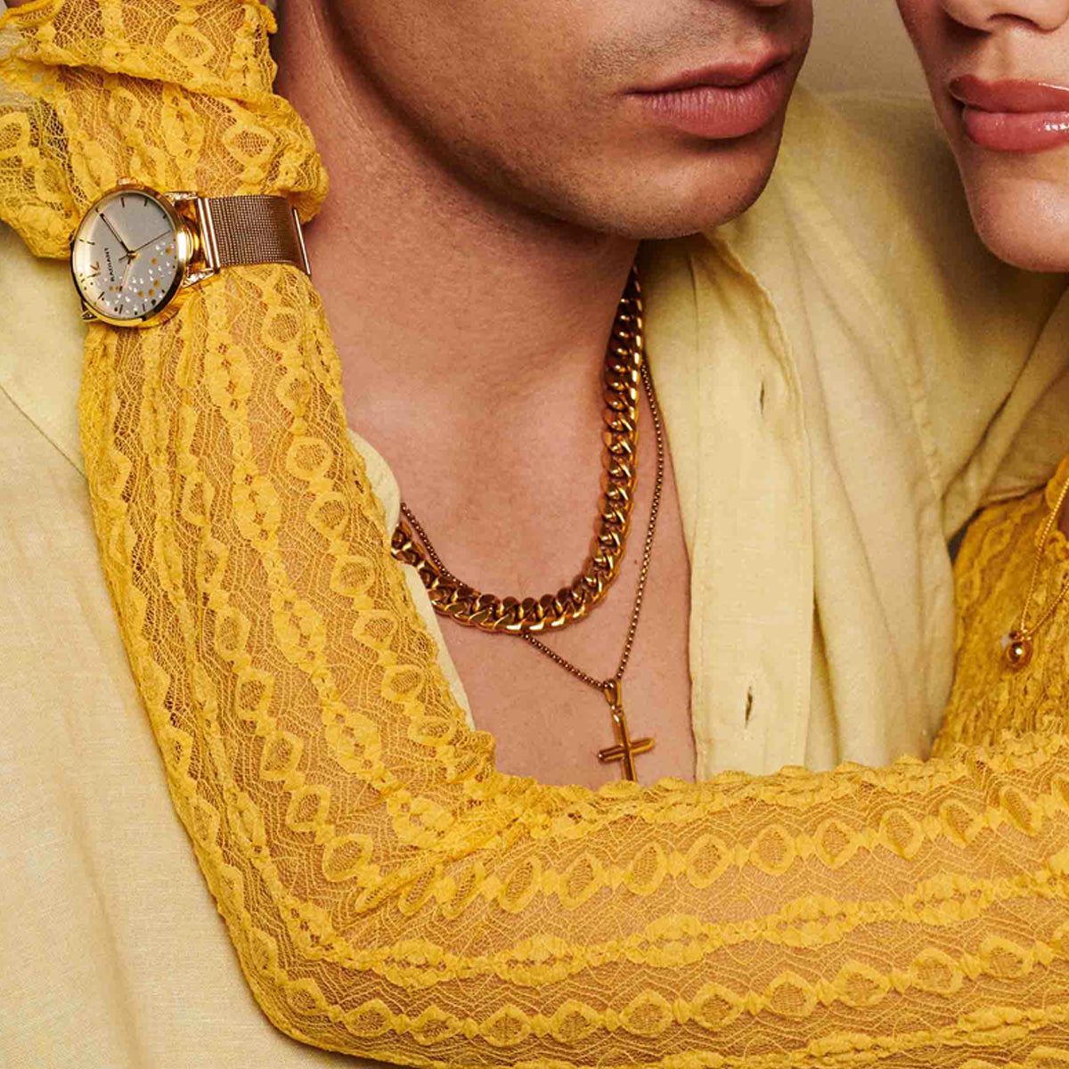 Couple wearing yellow lace, gold chain, and watch showcasing elegance and fashion.