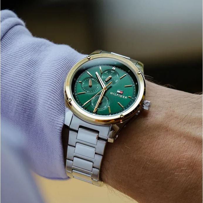 TOMMY HILFIGER Mod. 1710537 quartz analog gent's watch with mineral dial and 43mm case, worn on wrist, features green face and metal bracelet.