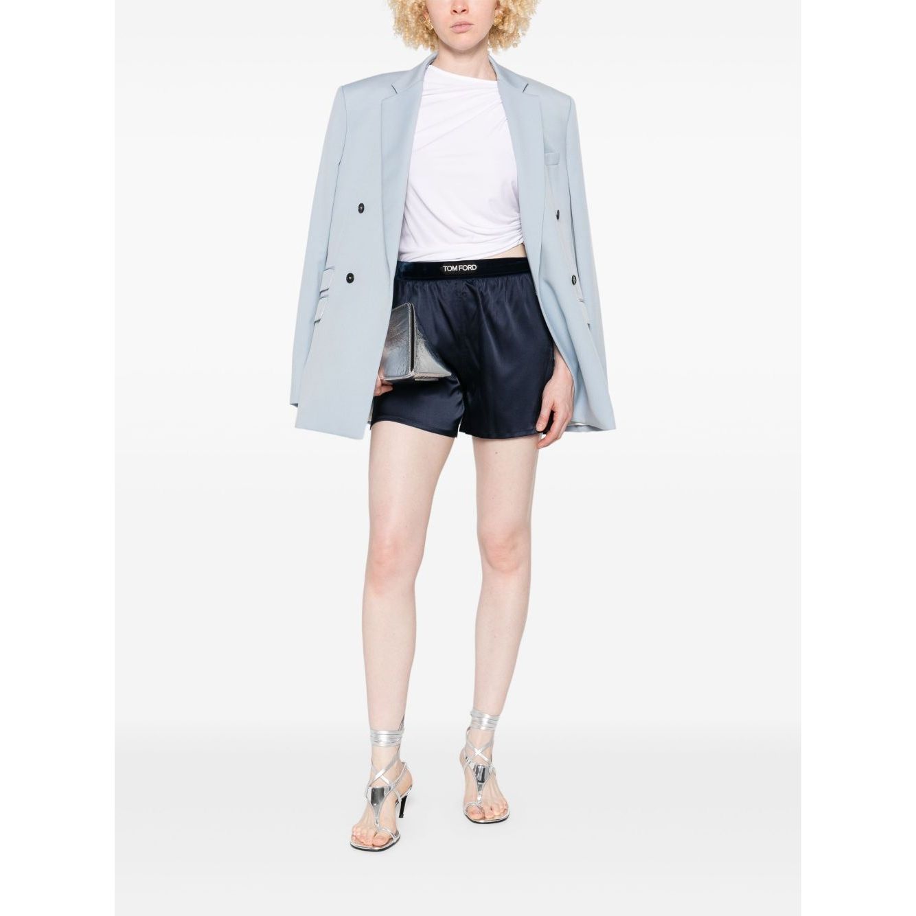 Model wearing Tom Ford Shorts Blue with navy elasticated waistband, paired with a light blazer and silver heels.