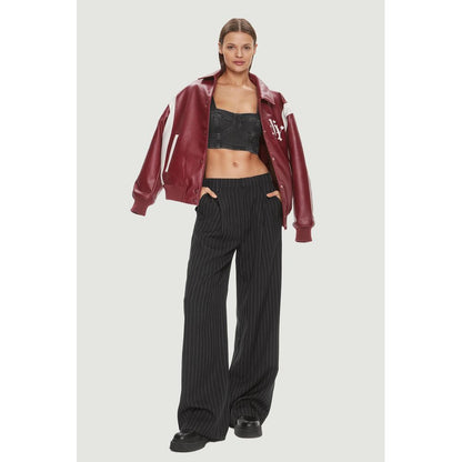 Woman wearing Tommy Hilfiger Jeans Black Recycled Cotton Top with red jacket and striped pants.