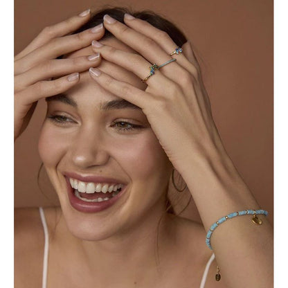 Smiling woman wearing a stylish ring and bracelet, showcasing jewelry accessories.