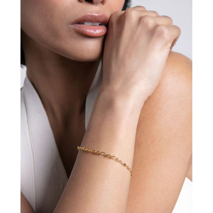 Woman wearing a gold chain bracelet on her forearm, showcasing elegant jewelry style.