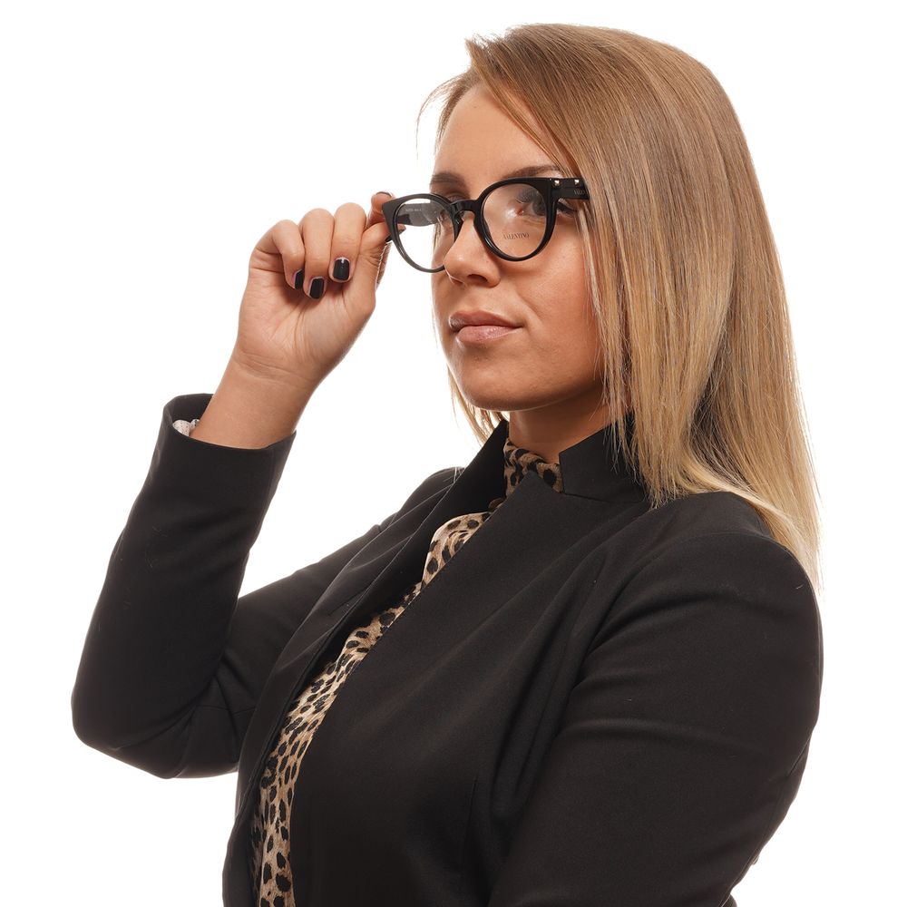 Woman wearing Valentino Black Women Glasses Frame, stylish round full-rim design, black plastic frame and demo lenses, professional look.