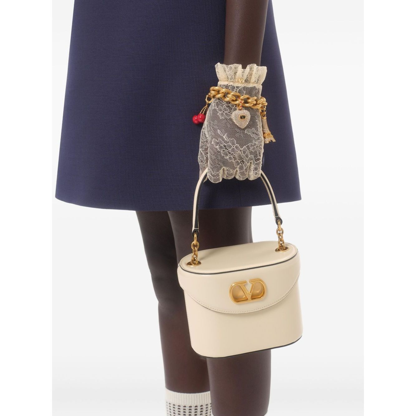 Woman holding a handbag wearing Valentino Short Embroidered Crepe Couture Dress, showcasing navy blue fabric with lace glove accessory.